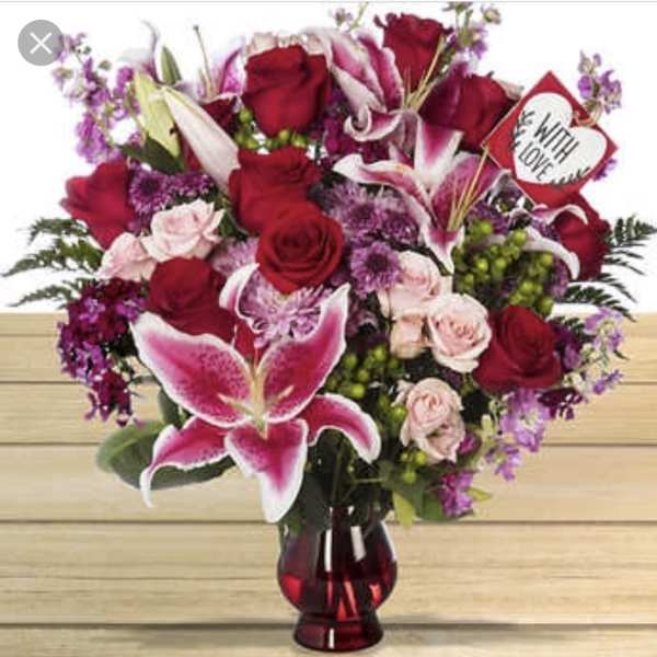 Red roses and pink lilies in a red glass vase with a heart sign
