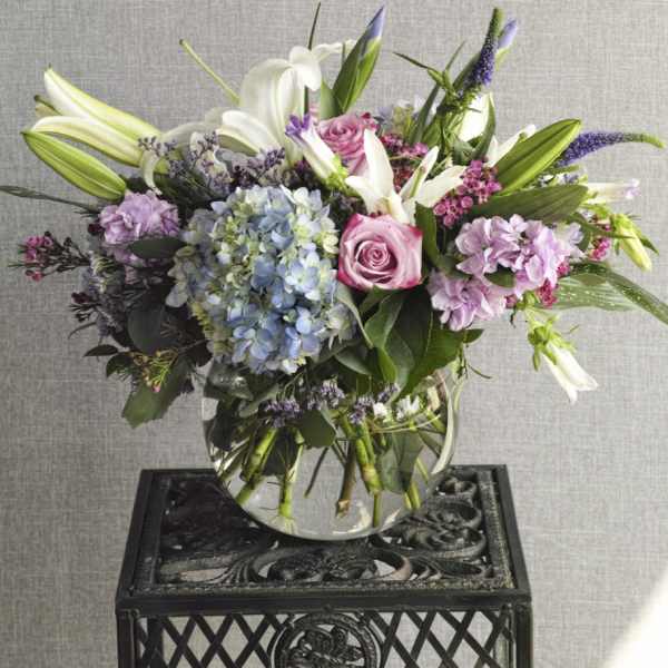 Mixed bouquet in a clear glass vase with lilies, roses, and hydrangeas