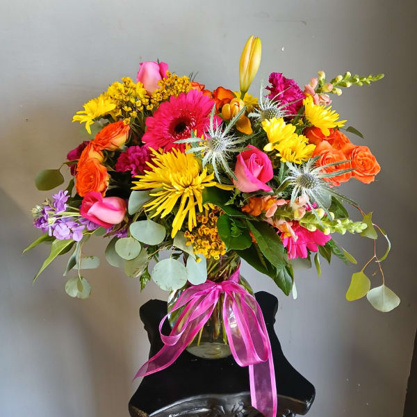 Colorful mixed bouquet in a glass vase with a pink ribbon
