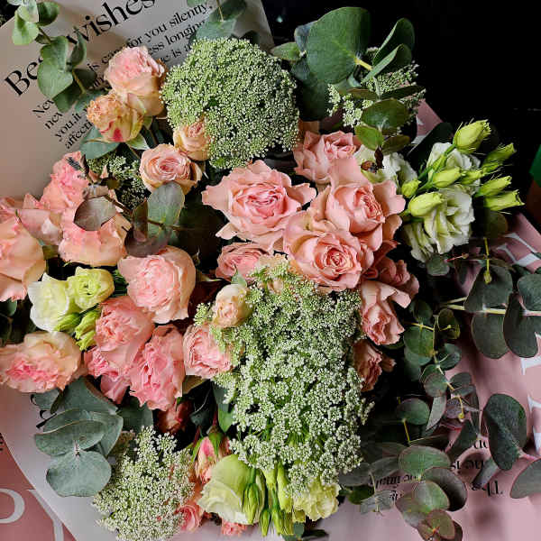 Bouquet of pink roses and white blooms with eucalyptus and a card