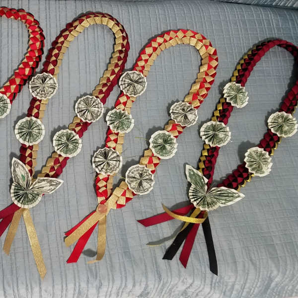 Four braided money garlands with ribbon tassels laid on a bed