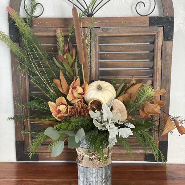 Autumn floral arrangement in a metal vase with a white pumpkin and dried accents