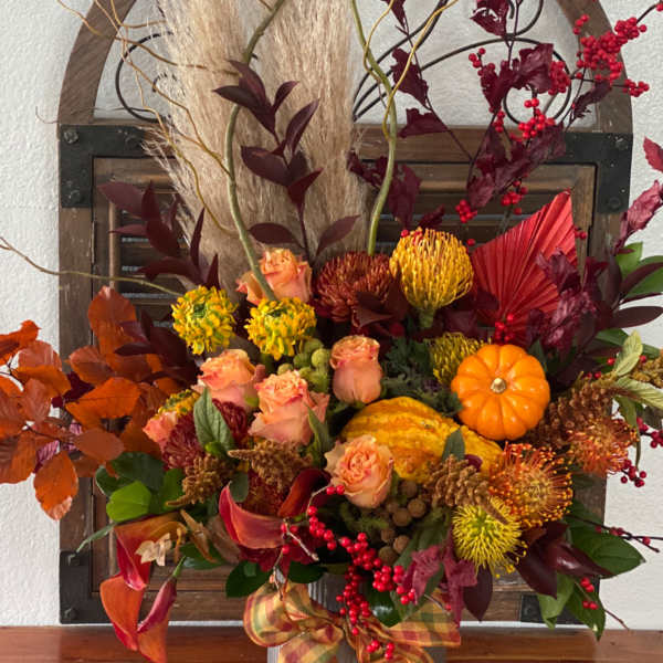Autumn floral arrangement with roses, mums, and pumpkins in a metal container