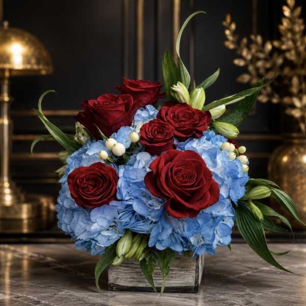 Red roses and blue hydrangeas arranged in a square vase