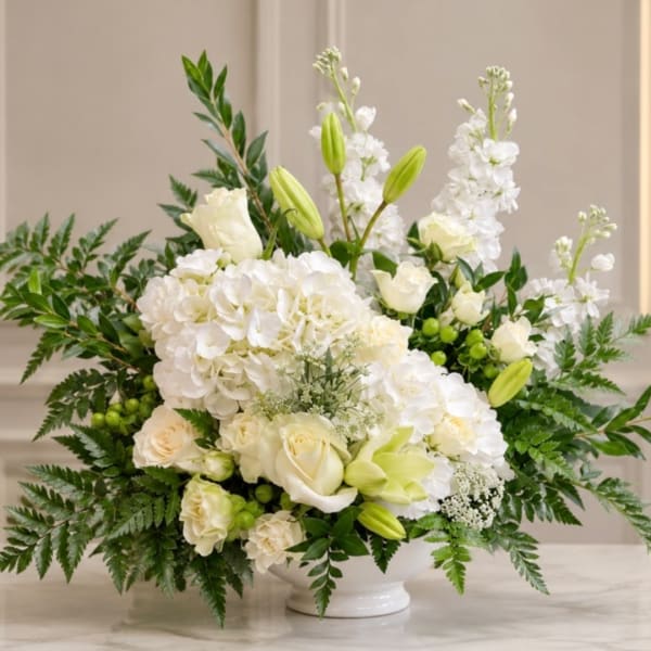 White floral arrangement in a white vase with green accents
