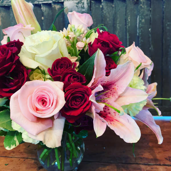Bouquet of pink and red roses with a pink lily in a glass vase