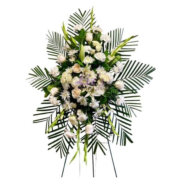 White funeral spray with roses, lilies, and daisies on palm fronds