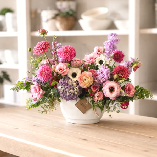 Mixed pink and lavender flowers arranged in a white bowl vase