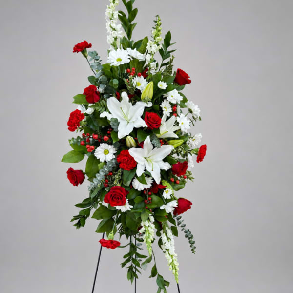 Tall red and white floral standing spray with lilies, roses, and daisies