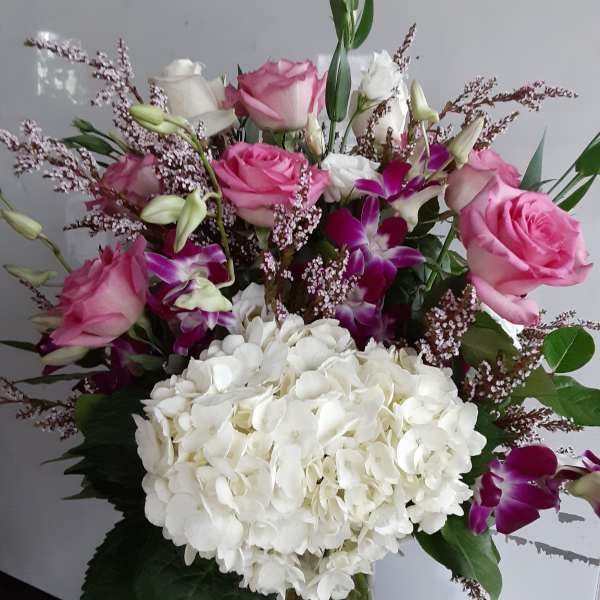 Bouquet of pink roses, white hydrangea, and purple orchids in a vase