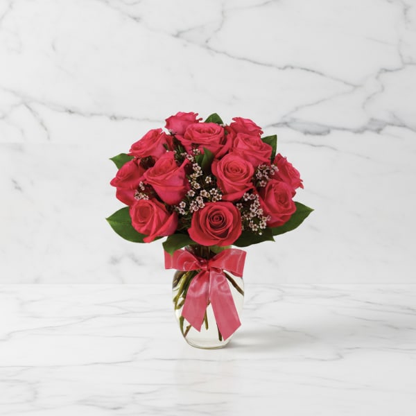 Pink rose bouquet in a clear glass vase with a ribbon