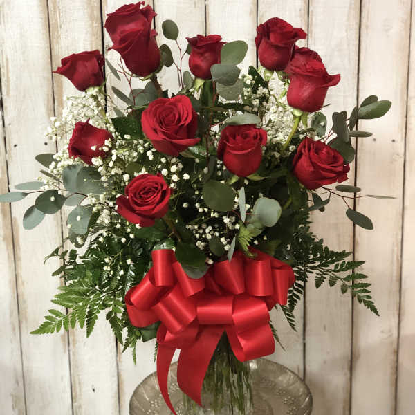 Red roses in a glass vase with a large red bow