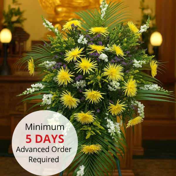Tall standing spray of yellow and white flowers on an easel in a temple setting