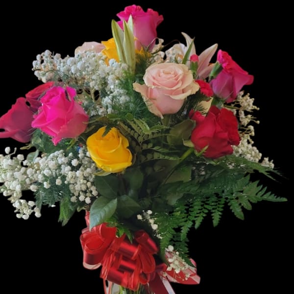 Mixed rose bouquet in a clear glass vase with a red ribbon