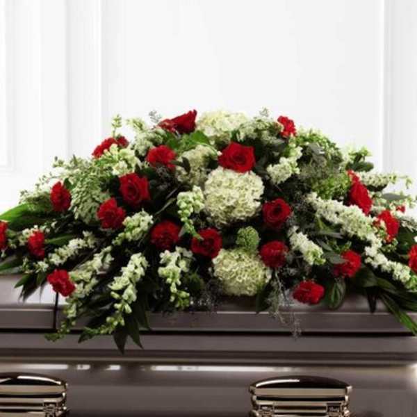 Red and white floral casket spray on a silver casket