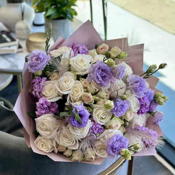 Bouquet of white roses and lavender flowers wrapped in pink paper