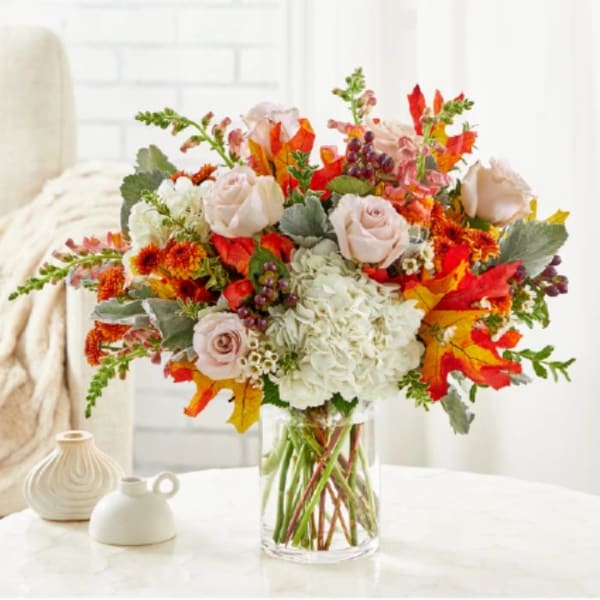 Autumn bouquet of pale roses and white hydrangea in a clear glass vase