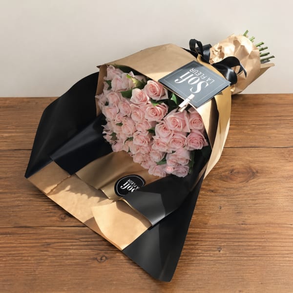 Bouquet of pale pink roses wrapped in black and kraft paper