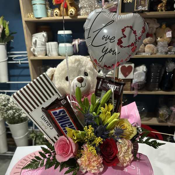 Flower and candy gift arrangement with a teddy bear and heart balloon