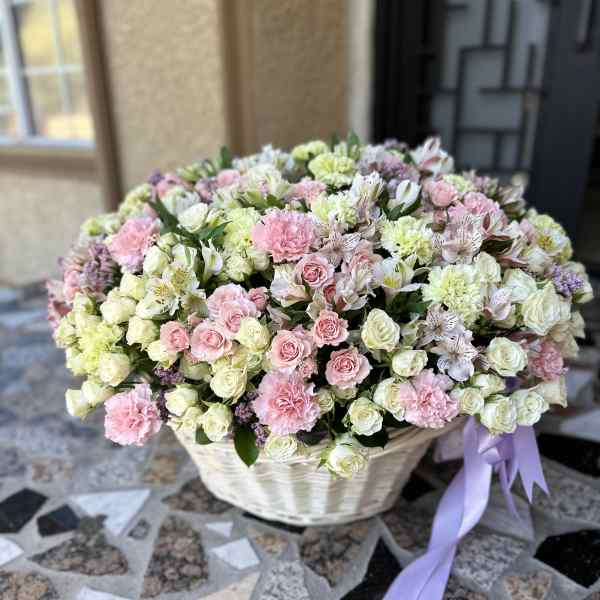 Large basket of pink and white flowers with a lavender ribbon
