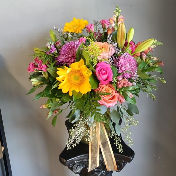 Mixed bouquet with sunflowers, roses, lilies, and purple mums in a vase