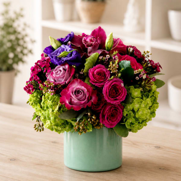 Pink and purple roses with green hydrangeas in a mint vase