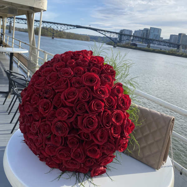 Large bouquet of red roses on a table by the water