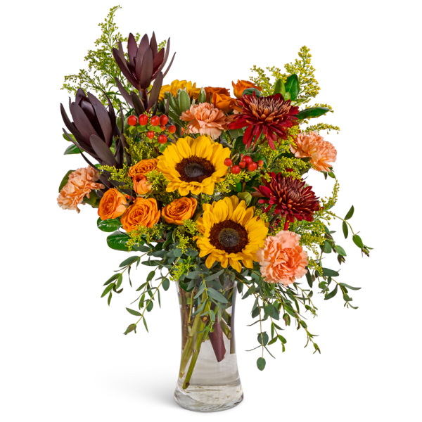Bouquet of sunflowers, orange roses, and carnations in a clear glass vase