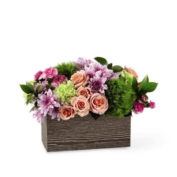 Pink and lavender flowers arranged in a wooden box