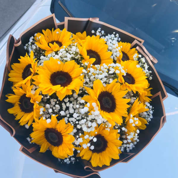 Bouquet of yellow sunflowers with white baby's breath in black wrap