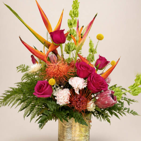 Tropical bouquet with magenta roses and orange bird-of-paradise in a gold vase