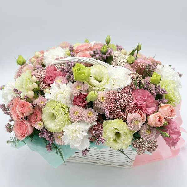 Pastel bouquet of pink, white, and green flowers in a white basket