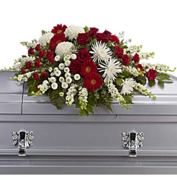 Red and white casket spray with roses, gerberas, and mums on a gray casket
