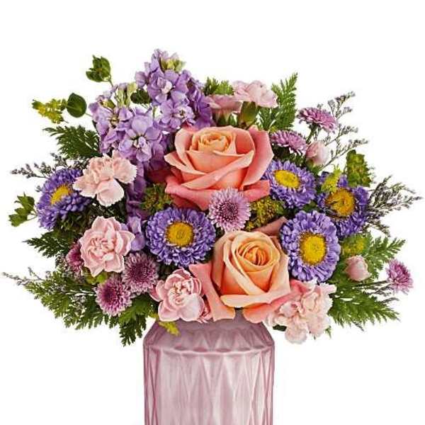 Pink and lavender flower arrangement in a mauve glass vase