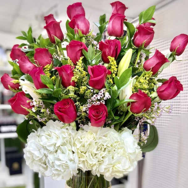 Tall arrangement of hot pink roses and white hydrangeas in a clear cylinder vase