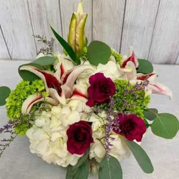 Bouquet of white lilies, red roses, and white hydrangeas with green accents