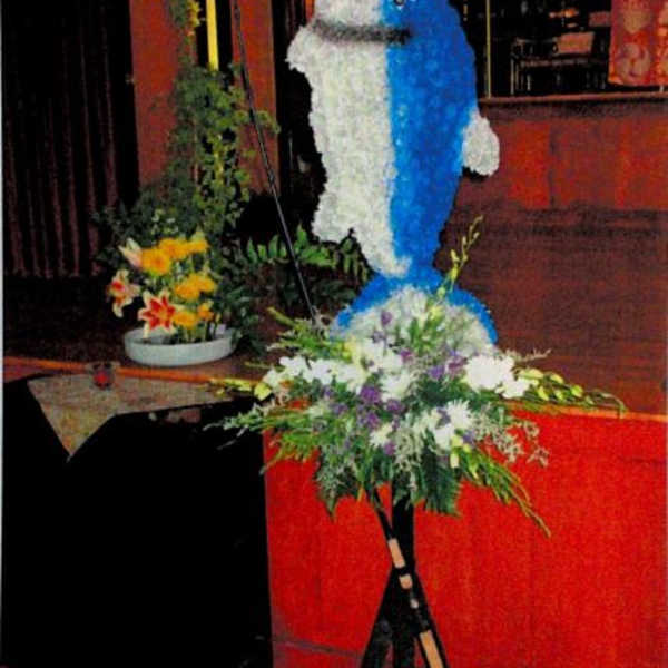 Large blue-and-white floral dolphin display on a stand with a flower arrangement at the base