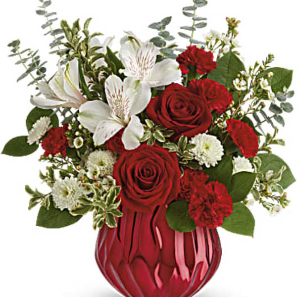 Red roses and white flowers arranged in a red glass vase