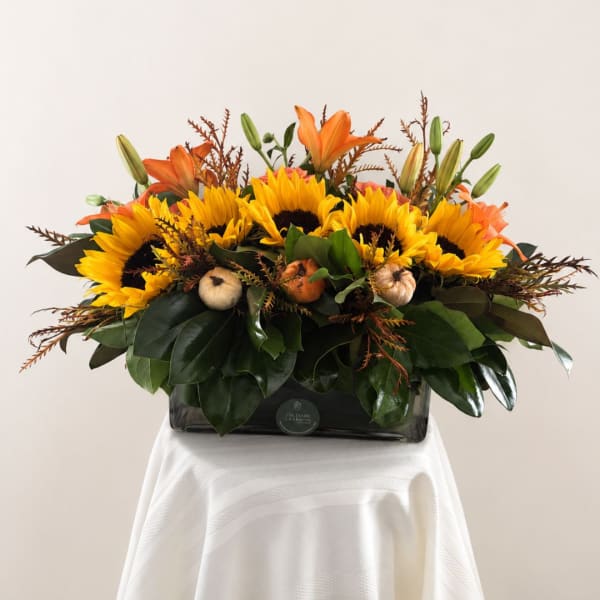Sunflowers and orange lilies arranged in a rectangular vase