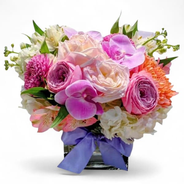 Pink and white mixed bouquet in a glass vase with a purple ribbon