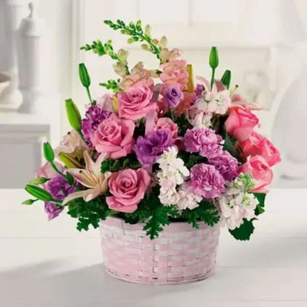Pink and purple flower arrangement in a pink basket