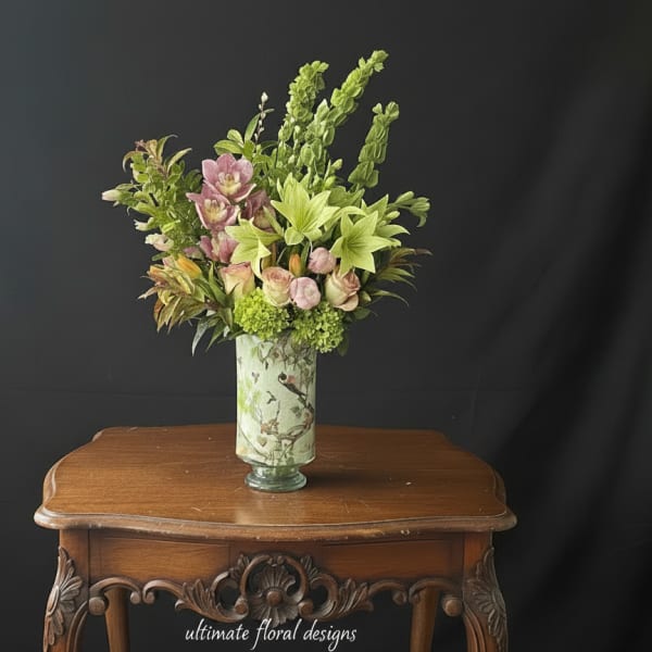 Tall floral arrangement in a decorative vase with pink and green blooms