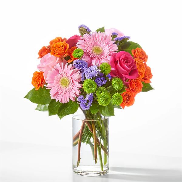Pink gerbera daisies and orange roses in a clear glass vase