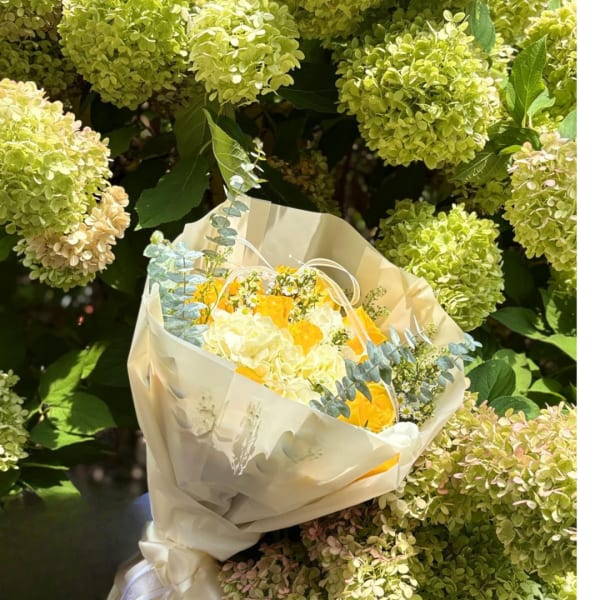 Yellow and white bouquet wrapped in cream paper with a ribbon