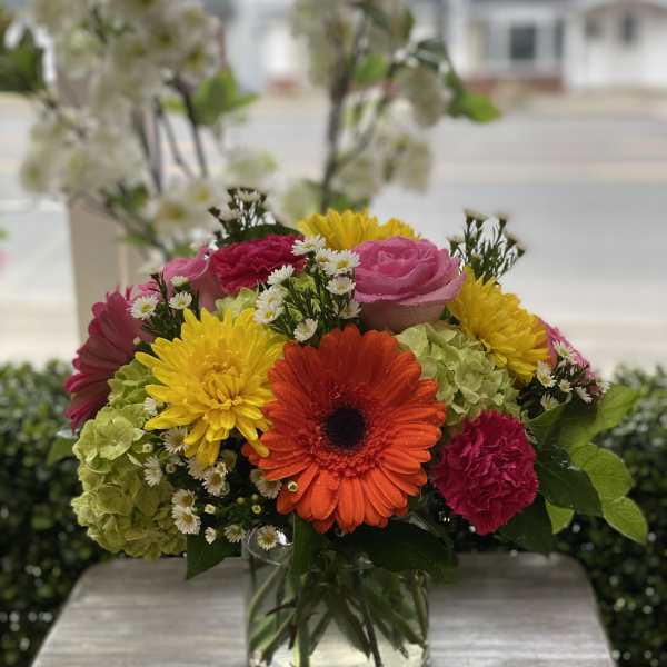 Mixed bouquet in a clear glass vase with bright gerbera daisies and roses