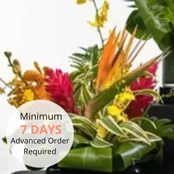 Tropical arrangement with orange, red, and yellow flowers in a low black container