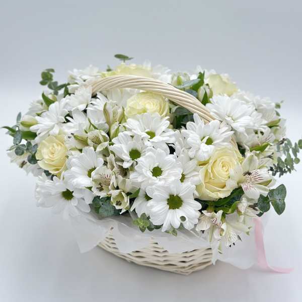 White daisies and cream roses in a wicker basket with a ribbon