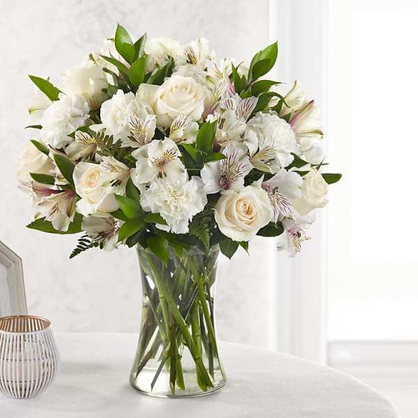 White roses and carnations arranged in a clear glass vase