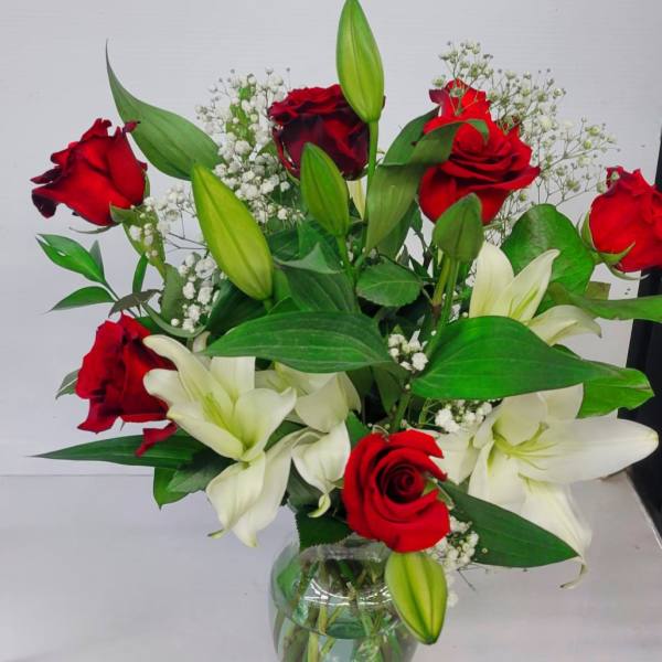 Red roses and white lilies arranged in a glass vase