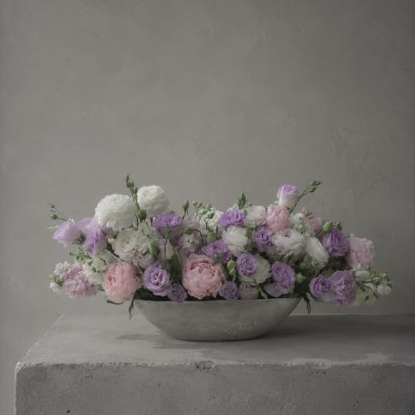 Low pastel flower arrangement in a shallow gray bowl